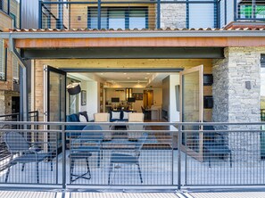 Ein offenes, modernes Haus mit einem Balkon, einem Essbereich und einer durch offene Türen einsehbaren Küche.