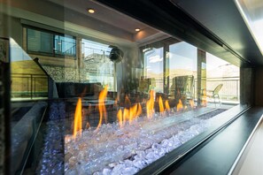 Ein modernes Interieur mit Kamin aus Glas, großen Fenstern und einer Wand mit Steinverkleidung.