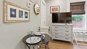 Een eetgedeelte met een tafel gedekt voor twee personen, een witte dressoir met lades, een spiegel en kunstwerken in lijsten aan de muur.