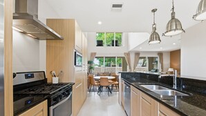 Una cocina moderna con estufa, horno y comedor con sillas y una mesa.