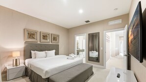 Una habitación de hotel moderna con una cama grande, mesitas de noche, un banco, un espejo y obras de arte en las paredes.