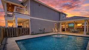 A two-story house with a swimming pool, a covered patio, and a TV in the living area. - PEL607 After Dune Delight, Private Heated Pool, Parking for 5 (Port Aransas)