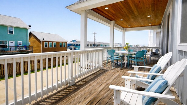A covered outdoor deck with white railings, a wooden ceiling, and outdoor seating with chairs and a table. - PEL607 After Dune Delight, Private Heated Pool, Parking for 5 (Port Aransas)