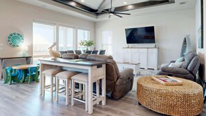 A modern living room with a dining area, a sofa, a TV, and a ceiling fan. - PEL607 After Dune Delight, Private Heated Pool, Parking for 5 (Port Aransas)