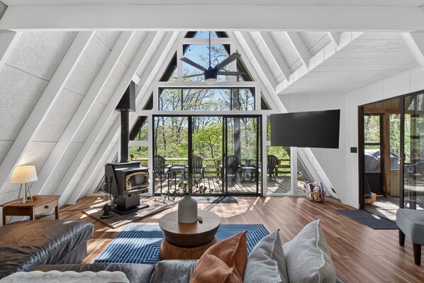 An attic room with a fireplace, seating area, and large windows.