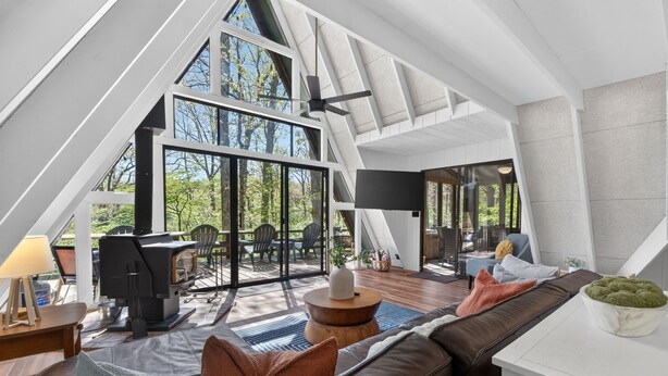 An attic-style room with a large window, a fireplace, a sofa, and a dining area.
