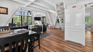 A modern interior with a dining area, a white refrigerator, and a staircase leading to an upper level.