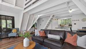 A modern interior with a leather sofa, wooden coffee table, and a staircase leading to an upper level.