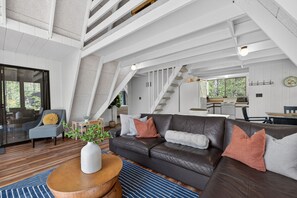 A modern interior with a leather sofa, wooden coffee table, and a staircase leading to an upper level.