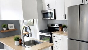 Een moderne keuken met een centraal eiland, roestvrijstalen apparatuur en witte kastjes.