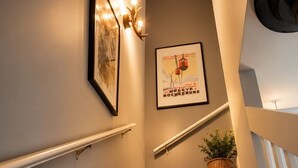 Een trap met een leuning, een lijst met een afbeelding en een poster aan de muur.