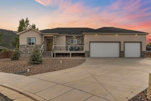 A two-story house with a stone facade, a front porch, and two attached garages. - Timeless Hive: Dual Primary + Dual Kitchen, Five-Bedroom, 3600 SF Family Retreat (Parowan)