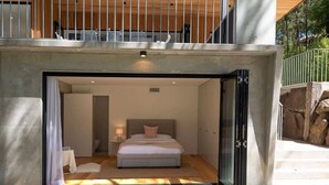 A modern bedroom with a large bed, a nightstand, and a window.