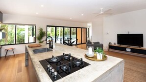 A modern kitchen with a central island, a built-in stove, and a large window offering a view of greenery.