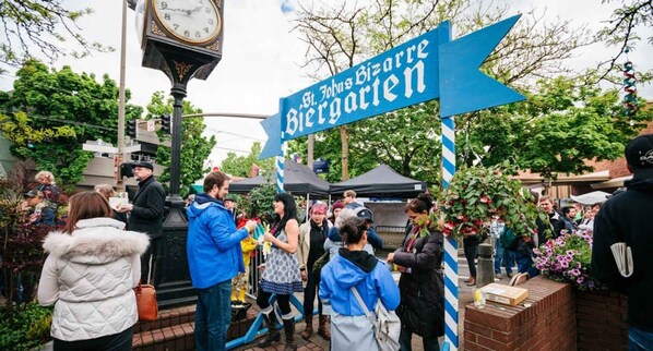 Une place publique avec une horloge, un panneau bleu et des gens rassemblés autour.