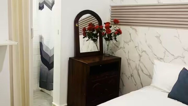 Een slaapkamer met een bed, een kaptafel, een spiegel en een deur naar een andere kamer.