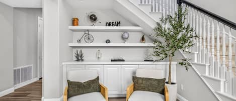A modern interior with a staircase, white walls, and a plant.