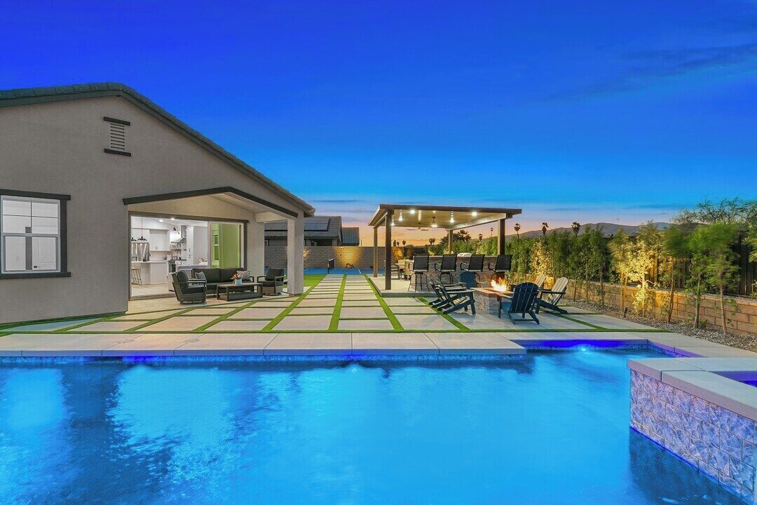A modern outdoor pool area with a covered patio and lounge chairs.