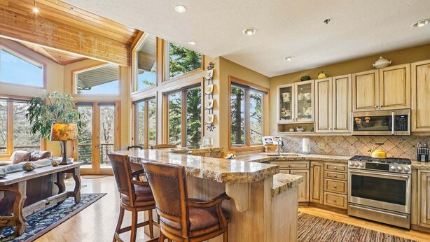 Una cocina amplia con una isla grande, armarios de madera y vistas al exterior.