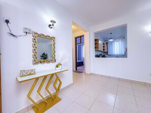 Ein modernes Interieur mit einer weißen Konsolentisch, einem goldfarben gerahmten Spiegel und einem Schild mit der Aufschrift 'HOME'.