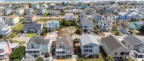 Una zona residencial costera con casas, una piscina y una playa al fondo.