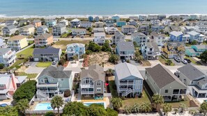 Un quartier résidentiel en bord de mer, avec des maisons, une piscine et une plage en arrière-plan.