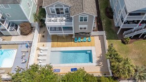 Ein zweistöckiges Haus mit Swimmingpool, Liegestühlen und einem eingezäunten Patio.