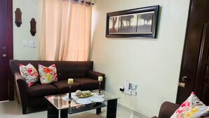 A living room with a brown sofa, a glass coffee table, and a framed picture on the wall.