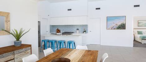 A modern kitchen with white cabinets, a blue backsplash, and a central island with stools.