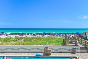 A beach view with a pool area, including a lifeguard stand, lounge chairs, and umbrellas. - Sundestin 205 (Destin)