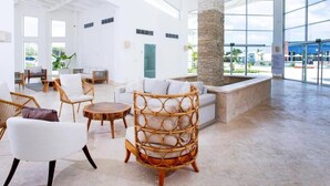 A spacious lobby with a high ceiling, large windows, and a central stone pillar. - Amazing Condo infinity Pool & Golf View at Cana Rock Condos (Punta Cana)
