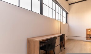Un interno moderno con una panca in legno, due sedie nere e un'ampia finestra.