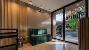 Un interior moderno con un sofá verde, una pared de madera y una puerta de cristal que da al exterior.
