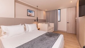 Una habitación de hotel moderna con una cama grande, un sofá, un televisor y un armario.
