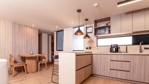 Una cocina moderna con armarios de madera, una mesa redonda para comer e iluminación colgante.
