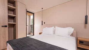 Un dormitorio moderno con cama, mesitas de noche, un armario y vistas al exterior.