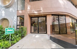 A building entrance with a glass door, a sign indicating a meeting point, and a paved walkway. - Jatisa 1001 in Medell n (Medellín)