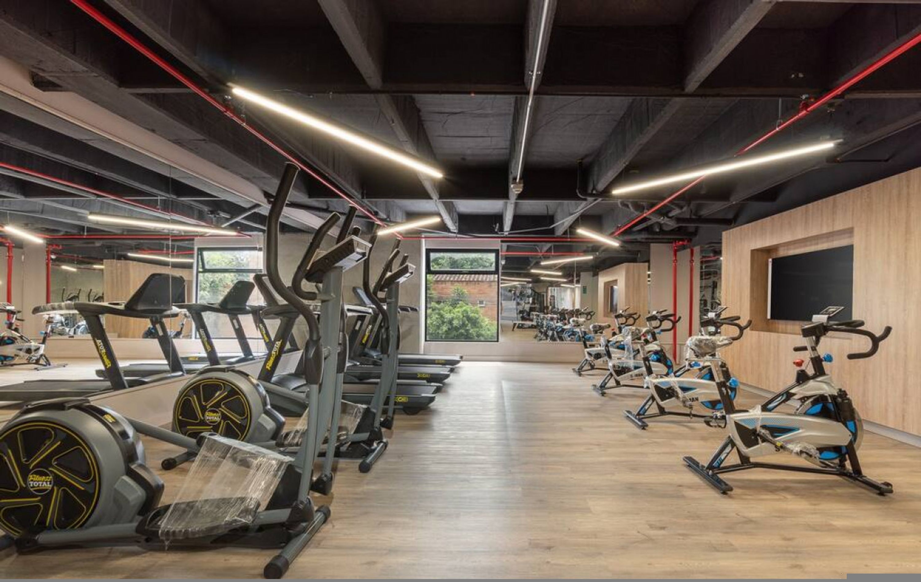 Uma academia com bicicletas ergométricas, esteiras e equipamentos de exercícios.