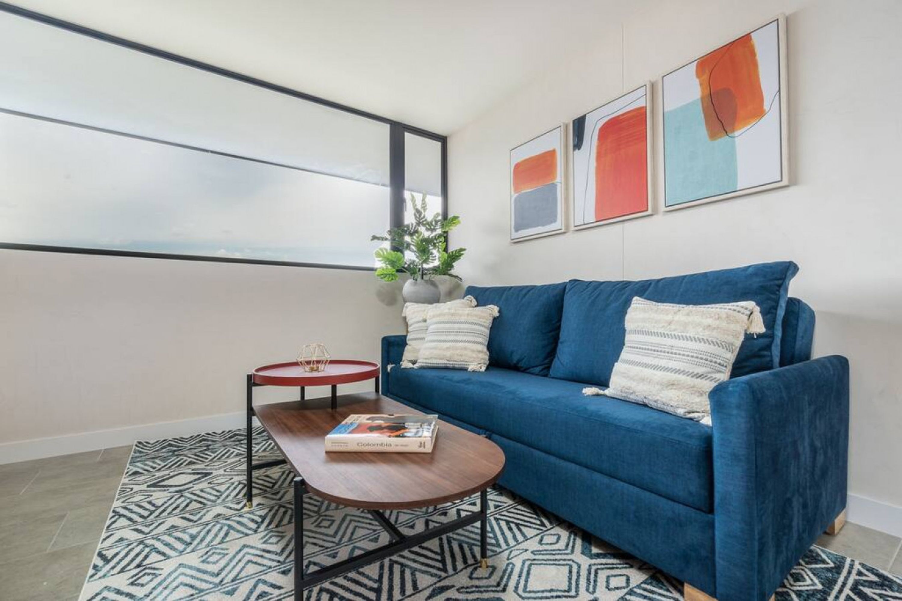 A modern living room with a blue sofa, a round coffee table, and a patterned rug.