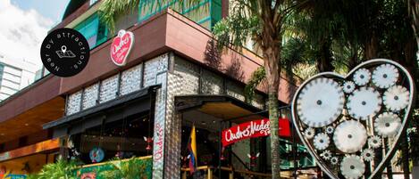 A building with a heart-shaped sculpture in front, a sign for 'Ode's Medellin,' and a mural on the wall.