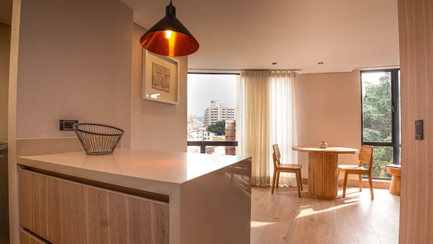 A modern kitchen with a wooden countertop, a hanging pendant light, and a view of the city through large windows. - Jatisa 901 in Medell n (Medellín)