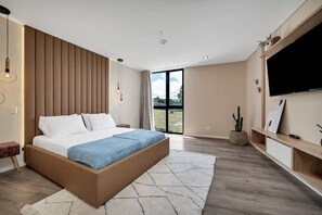 A modern bedroom with a large bed, a TV, and a sliding glass door to the outside. - Olive Country Living - 301 (Envigado)