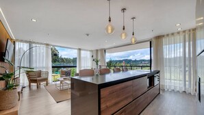 A modern kitchen with a large island, wooden cabinets, and pendant lighting. - Olive Country Living - 301 (Envigado)