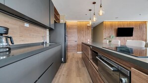 A modern kitchen with a built-in oven, a coffee machine, and a flat-screen TV mounted on the wall. - Olive Country Living - 301 (Envigado)