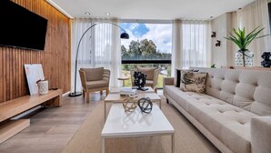A modern living room with a sofa, coffee table, and a TV mounted on a wooden wall. - Olive Country Living - 301 (Envigado)