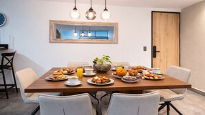 A dining table with plates of food, a vase with flowers, and hanging pendant lights. - Oslo 701 in Medell n (Medellín)