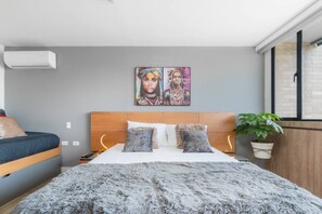 Een slaapkamer met een bed, een hoofdbord, een wandairconditioner en een raam met uitzicht.