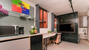 A compact kitchen with a microwave, coffee maker, and a small refrigerator. There is a dining area with a chair and a table. A large TV is mounted on the wall. - Ayamonte 301a in Medell n (Medellín)