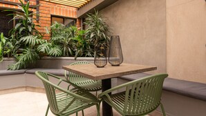 A patio area with a table and chairs, surrounded by plants and a brick wall. - Ayamonte 301a in Medell n (Medellín)
