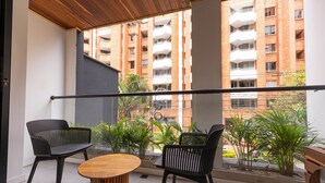 A balcony with two black chairs, a wooden table, and potted plants. - Opera 403 in Medell n (Medellín)